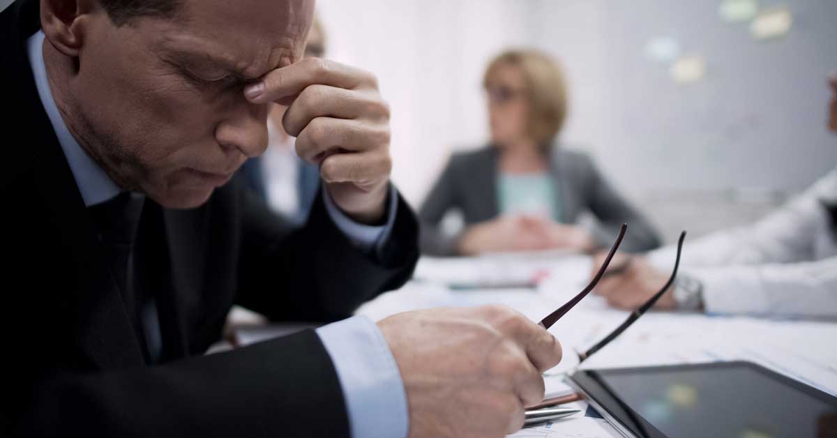 Businessman in a meeting holding his forehead as if he has a headache