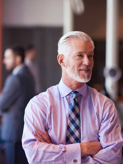 Mature man with a grey beard wearing a lical short and patterned tie